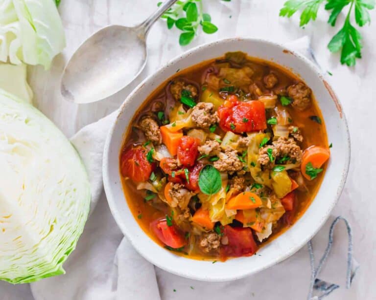 A bowl of cabbage soup with meat and vegetables.