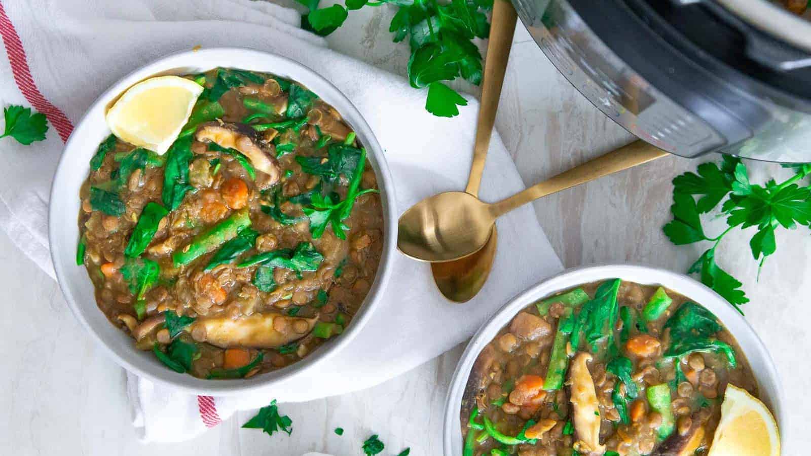 Instant Pot lentil vegetable soup in two white bowls with fresh parsley and lemon wedges.