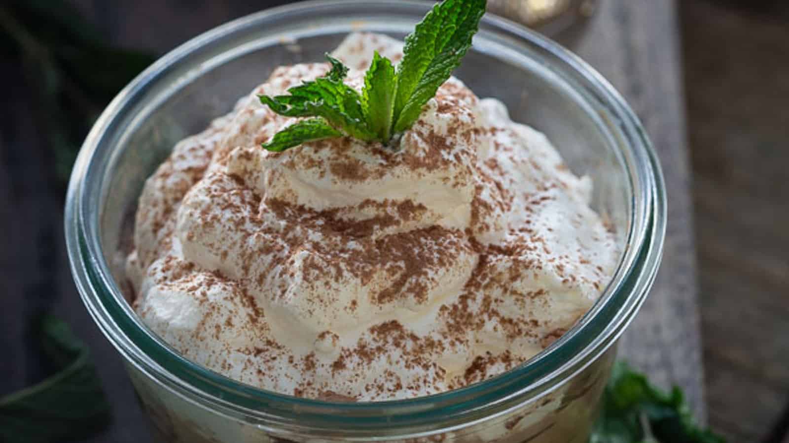 No bake Irish cream cheesecake in a glass jar garnished with mint leaf.