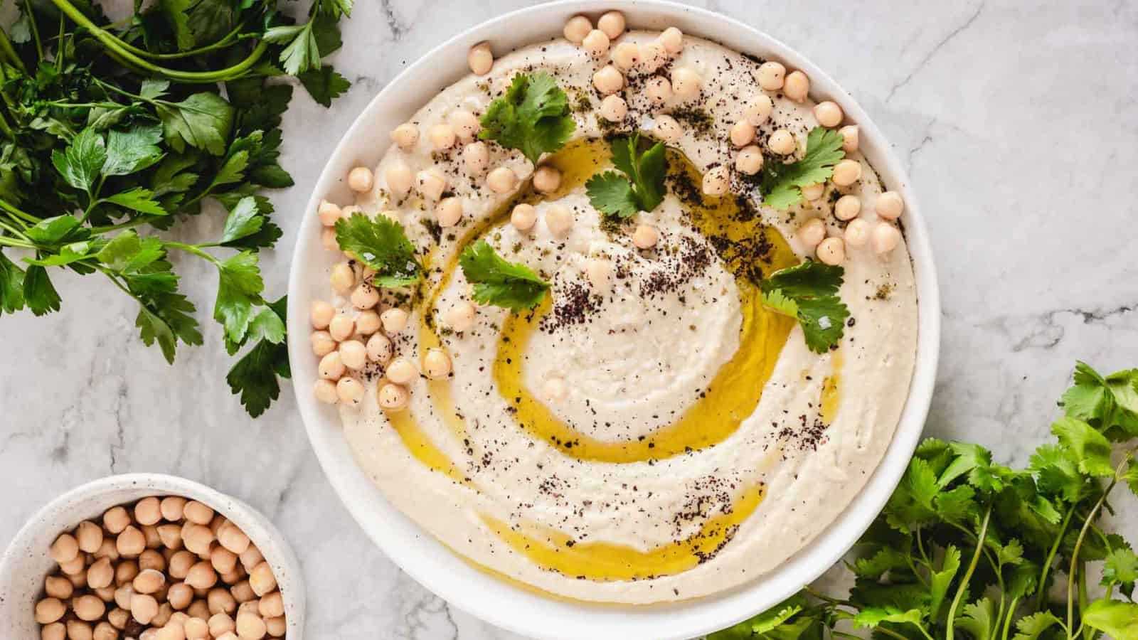 Garlic hummus on plate with parsley, zaatar and olive oil.