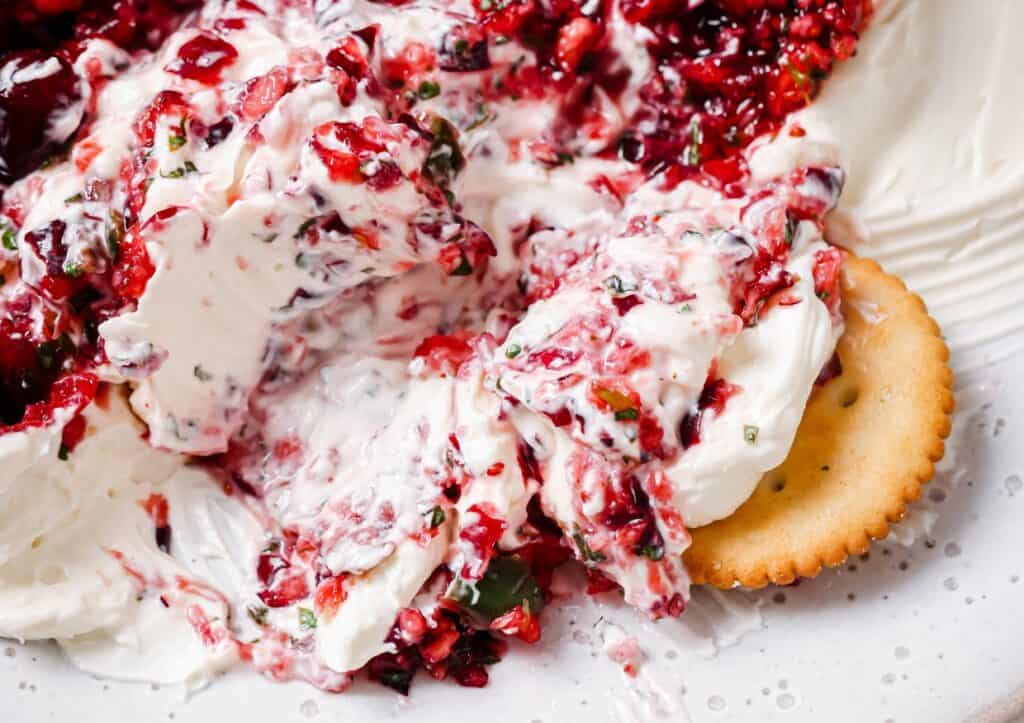 A plate with cranberry cream cheese and crackers.