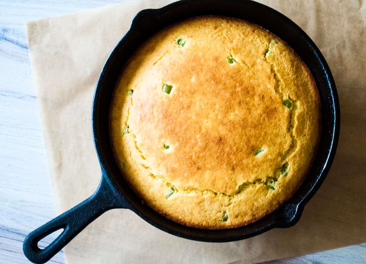 A cast irons skillet with jalapeño corn bread in it.