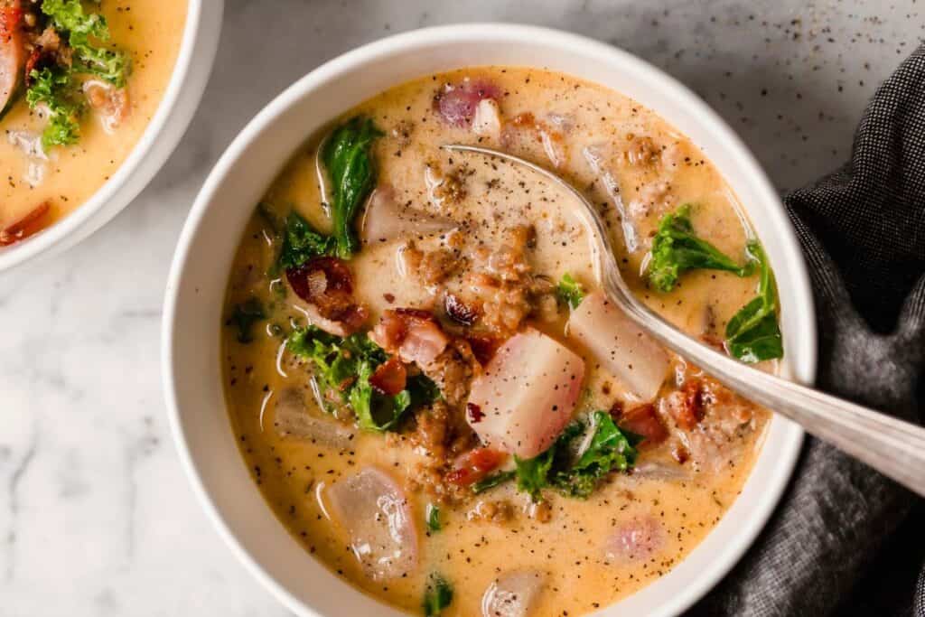 Two bowls of soup with bacon and kale.