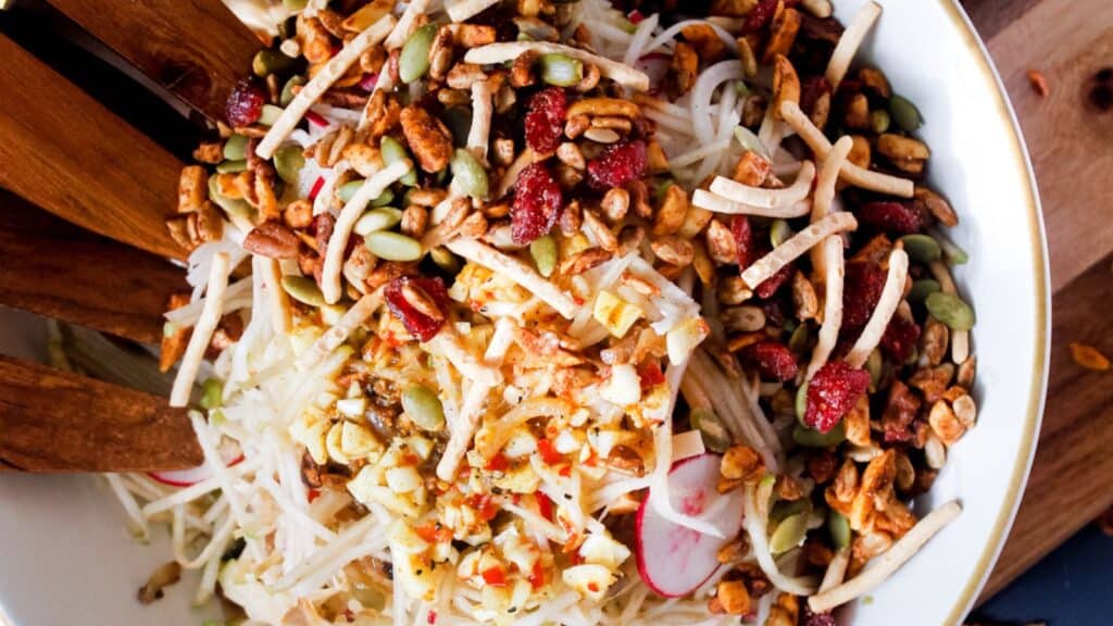 A bowl of salad with nuts and seeds in it.