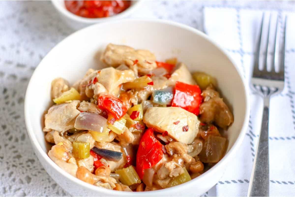 Chinese chicken stir fry with peppers and onions in a white bowl.