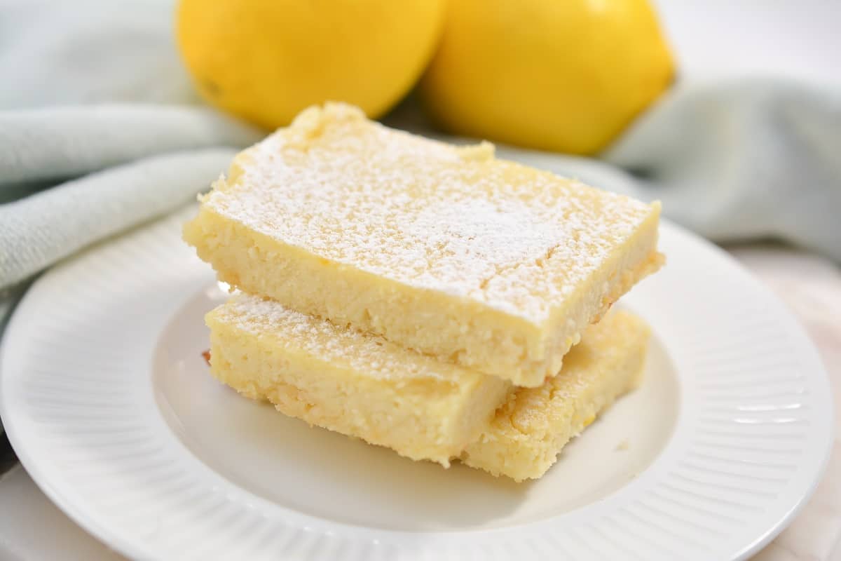 Lemon bars with powdered sugar on a white plate.