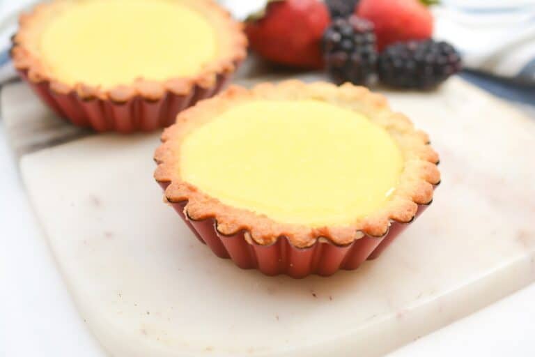 Two lemon tarts sitting on a cutting board.