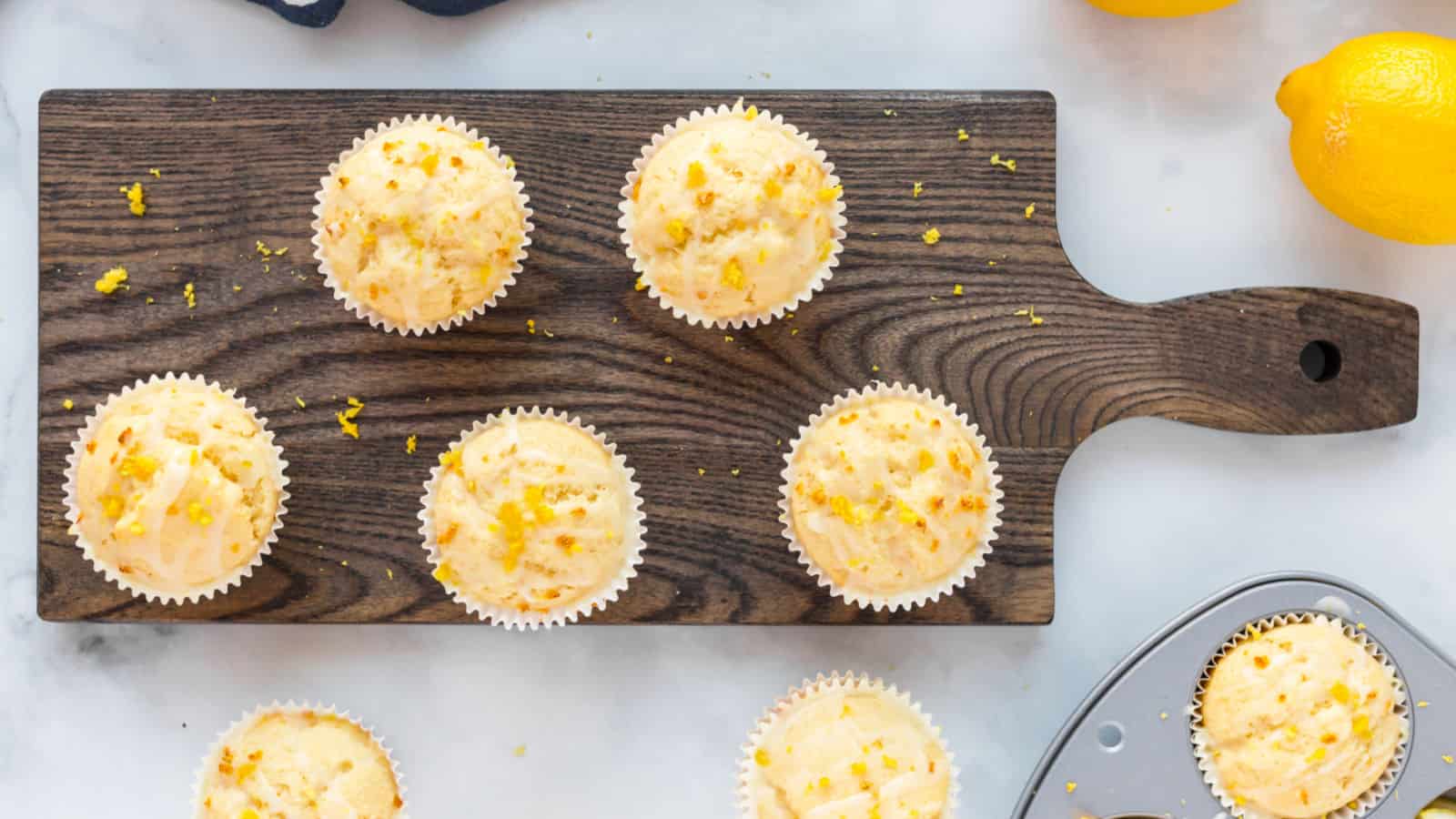 Lemon muffins on a wood cutting board.