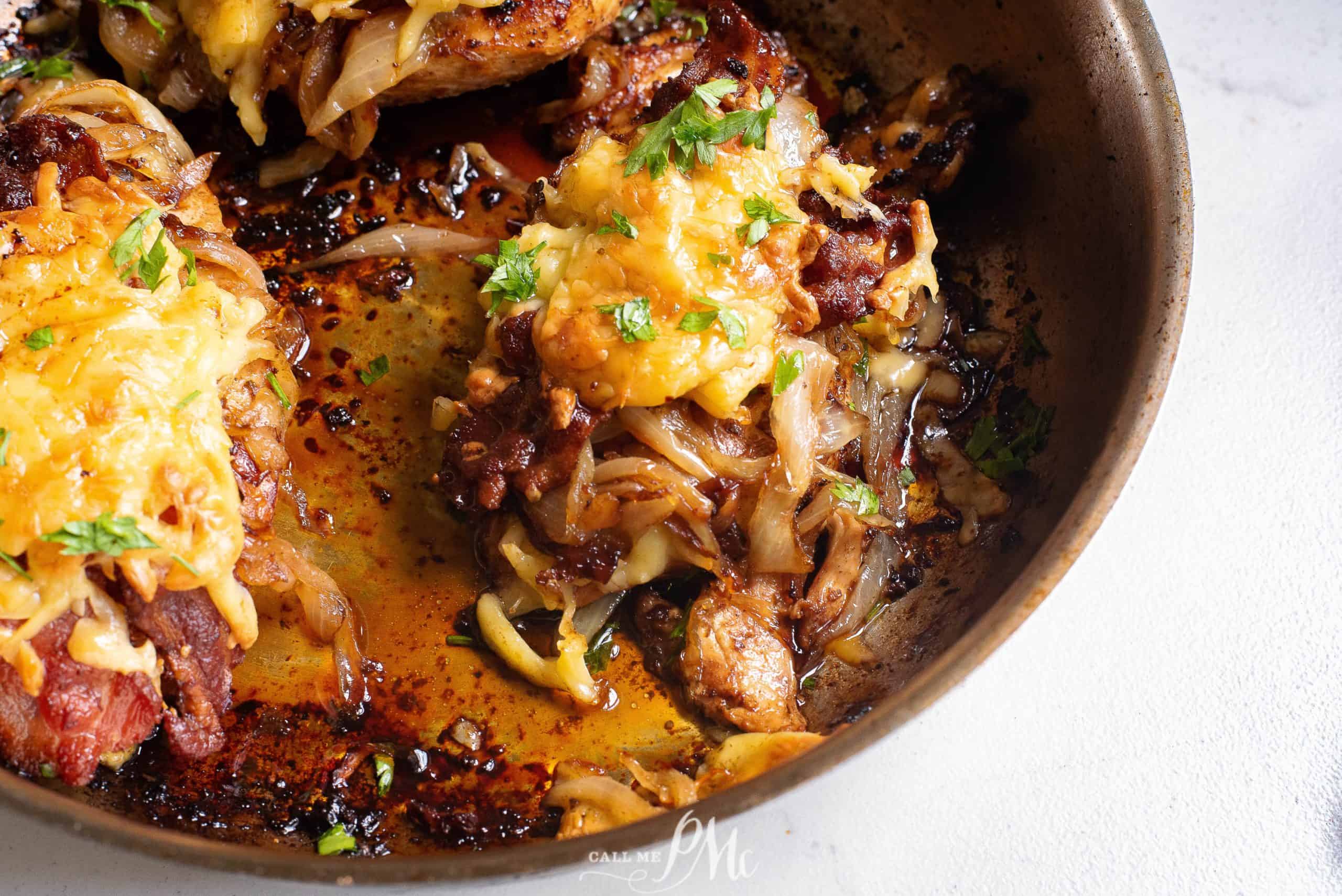 Chicken breasts in a skillet covered with onions and cheese.