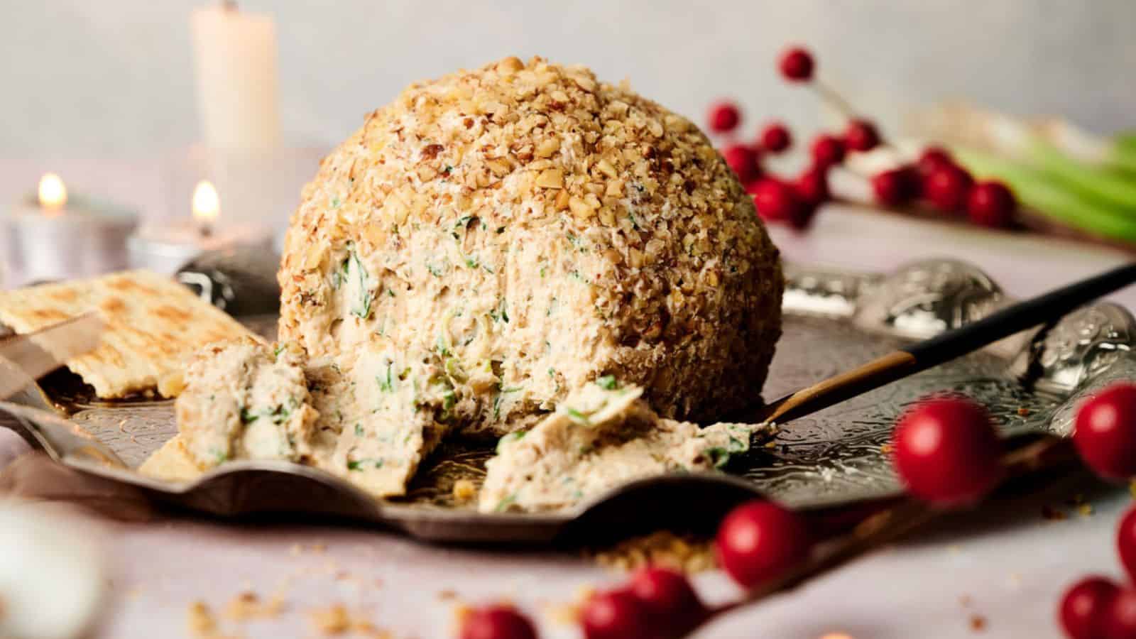 A cheese ball on a cutting board with crackers.