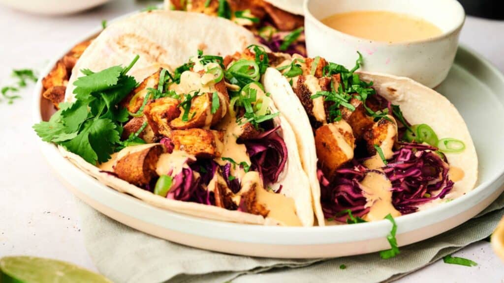 Sweet potato tacos on white plate with chipotle sauce.