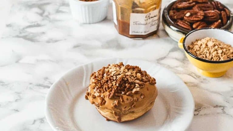 A delicious Hanukkah dessert featuring a plate topped with a decadent donut drizzled with creamy peanut butter and sprinkled with crunchy pecans.