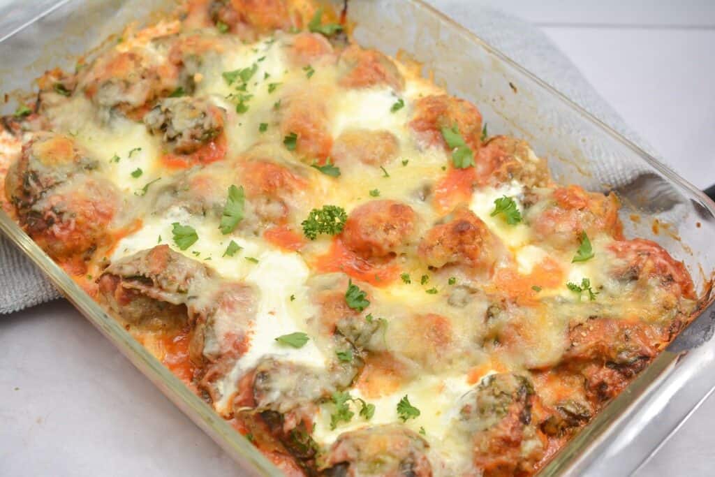 A casserole dish filled with meatballs and cheese.