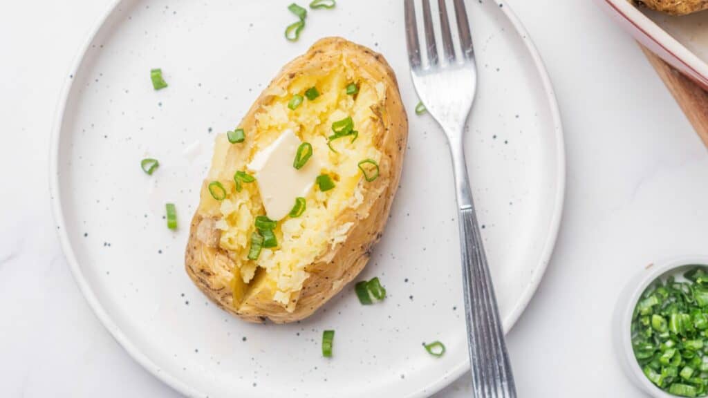 Baked potatoes on a white plate with a fork.