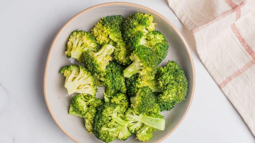 A plate of broccoli on a white table.