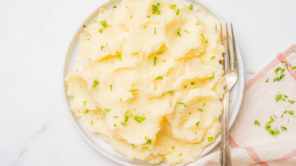 Mashed potatoes on a white plate with a fork.