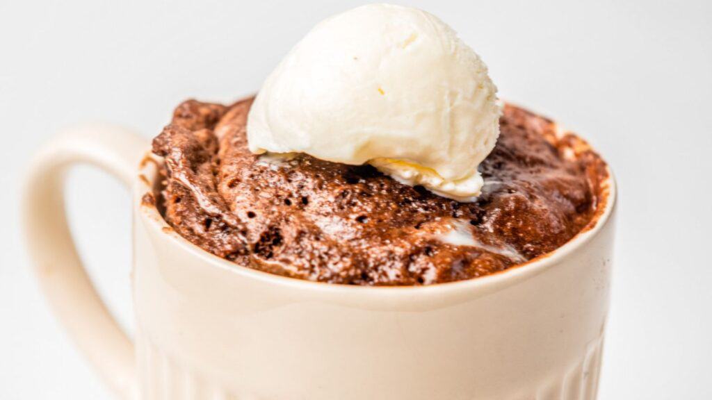 A mug of chocolate pudding with a scoop of ice cream on top.
