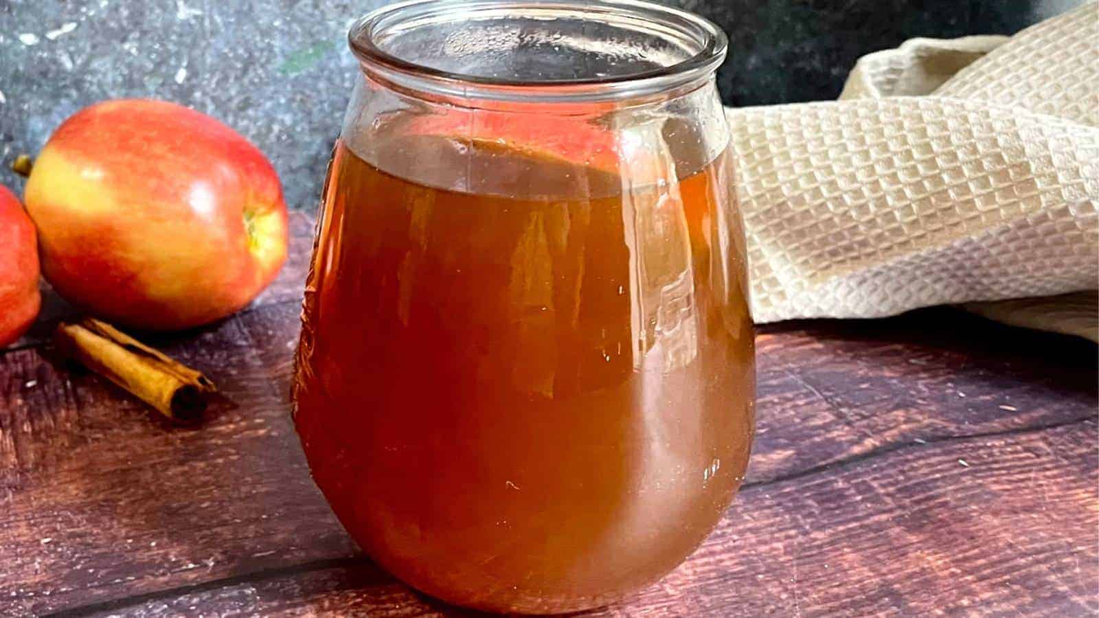 A jar of non-alcoholic apple cider on a wooden table.