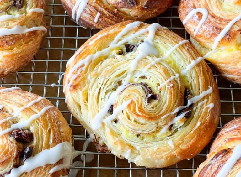 Raisin pastries with icing on a cooling rack.