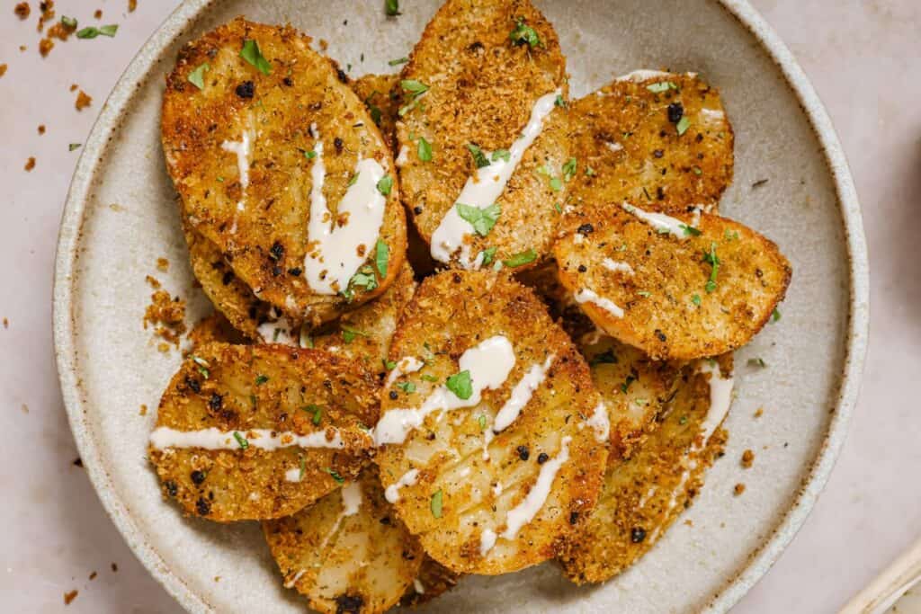 Parmesan crusted potatoes on a plate with dipping sauce.