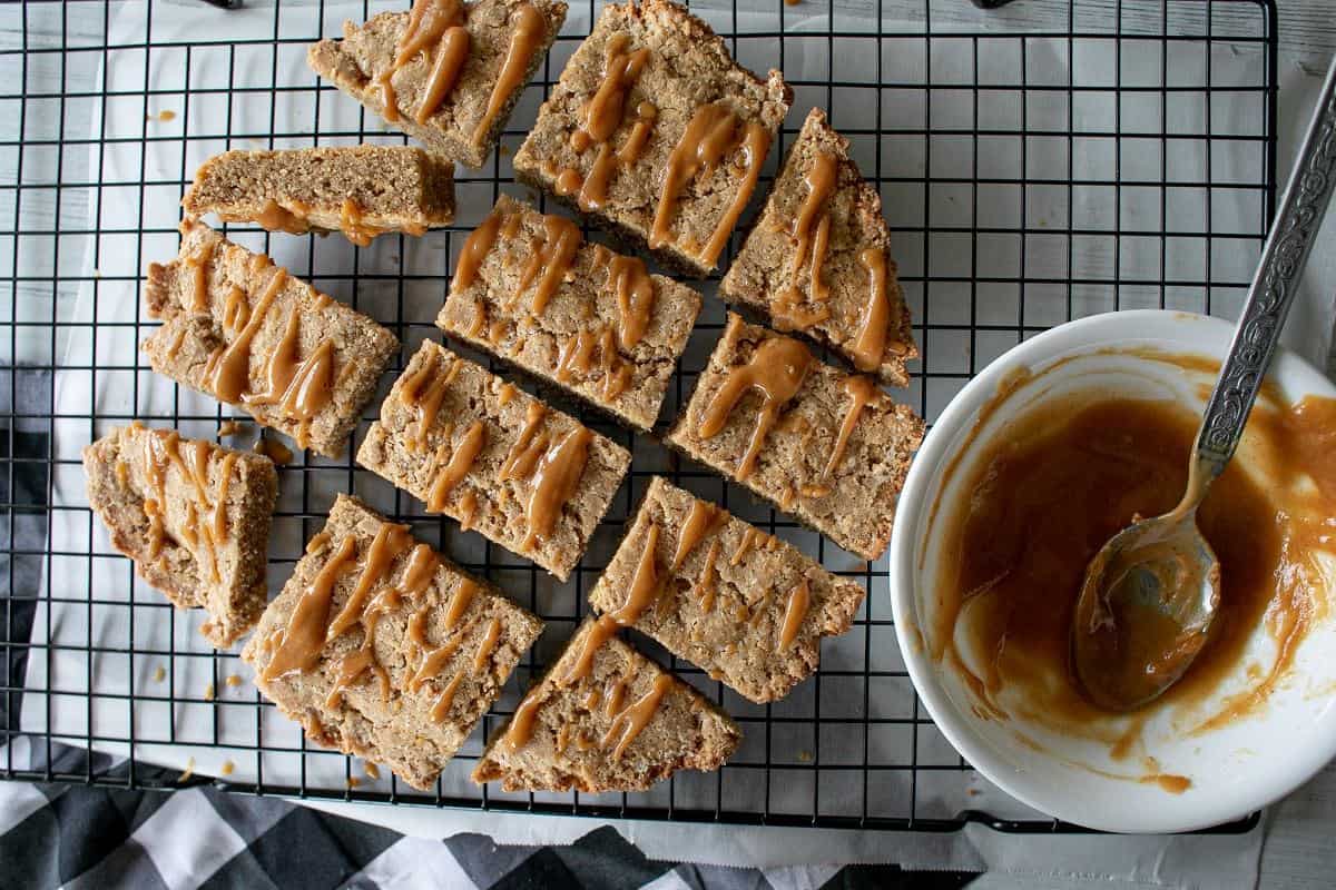 A cooling rack with slices of bread and a bowl of caramel sauce.
