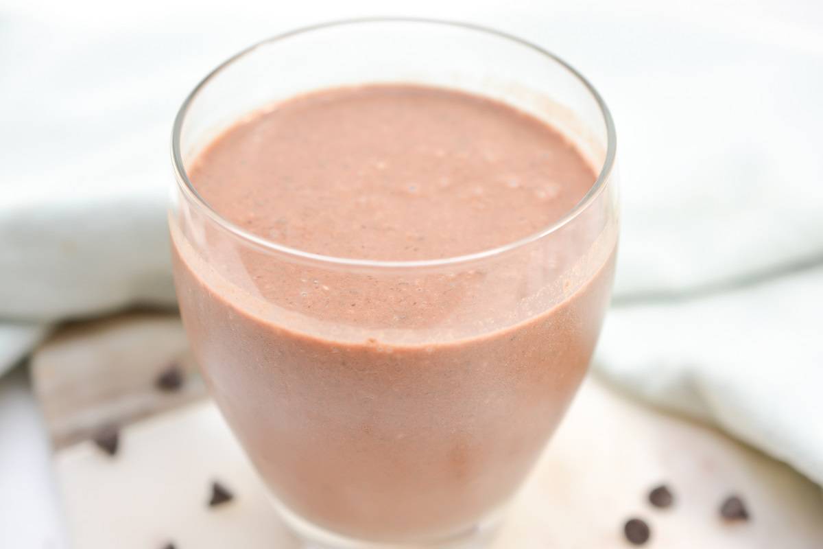 A chocolate and peanut butter smoothie in a glass with chocolate chips.