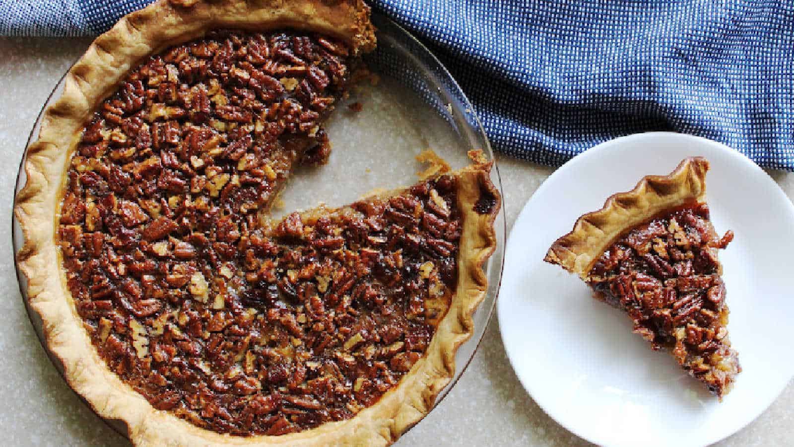 Pecan pie on a plate with a slice taken out.