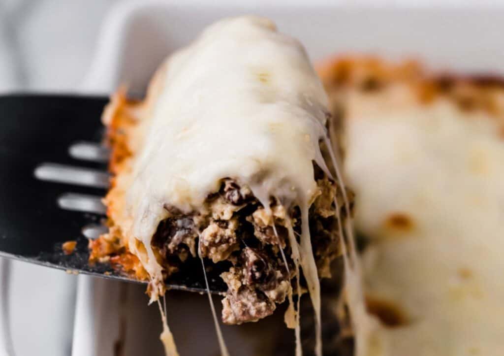 A fork is being used to take a piece of Philly cheese steak casserole out of a dish.