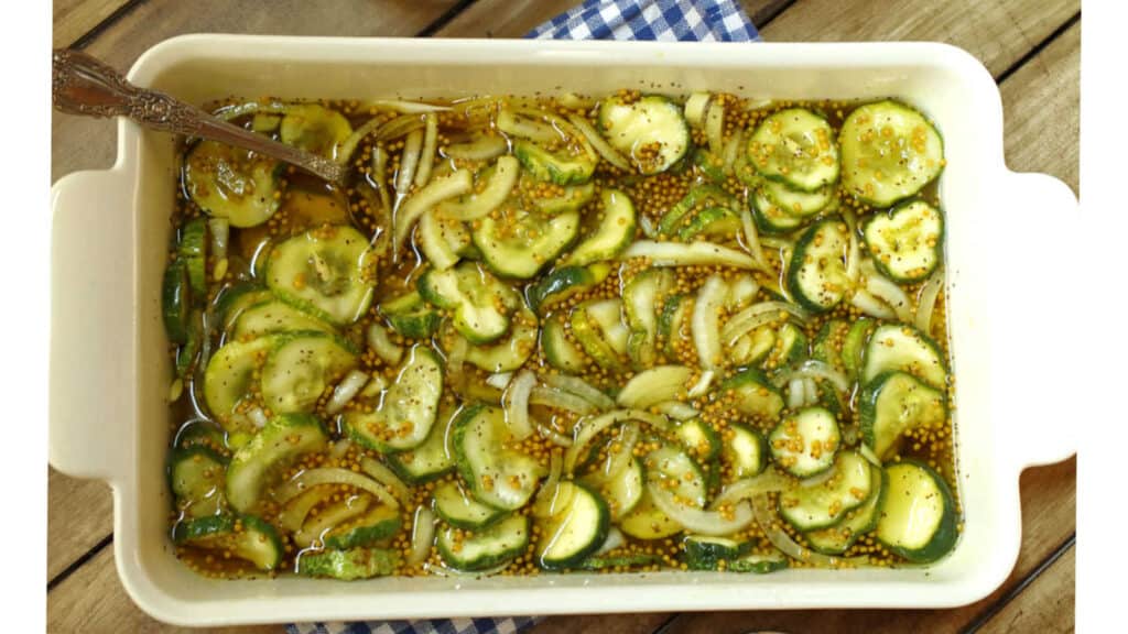 Bread and butter pickles in a white dish.