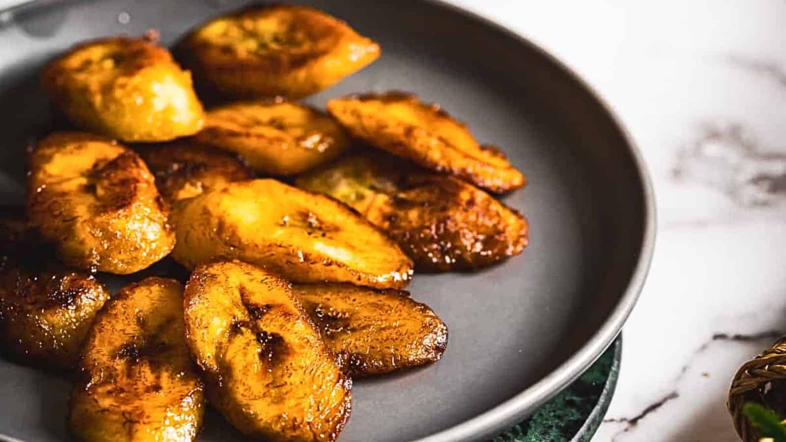 A plate of fried bananas on a marble table.