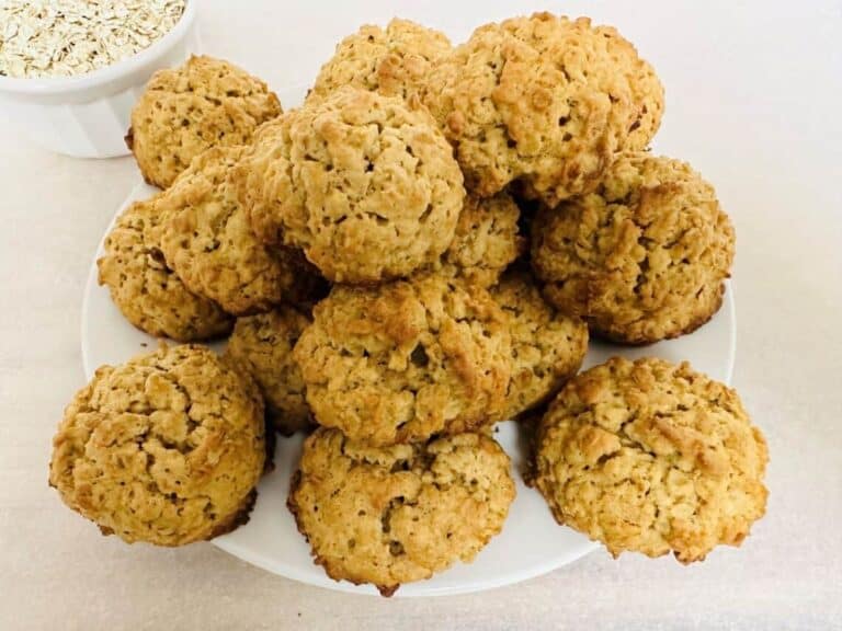 Oatmeal cookies on a plate next to a bowl of oats.