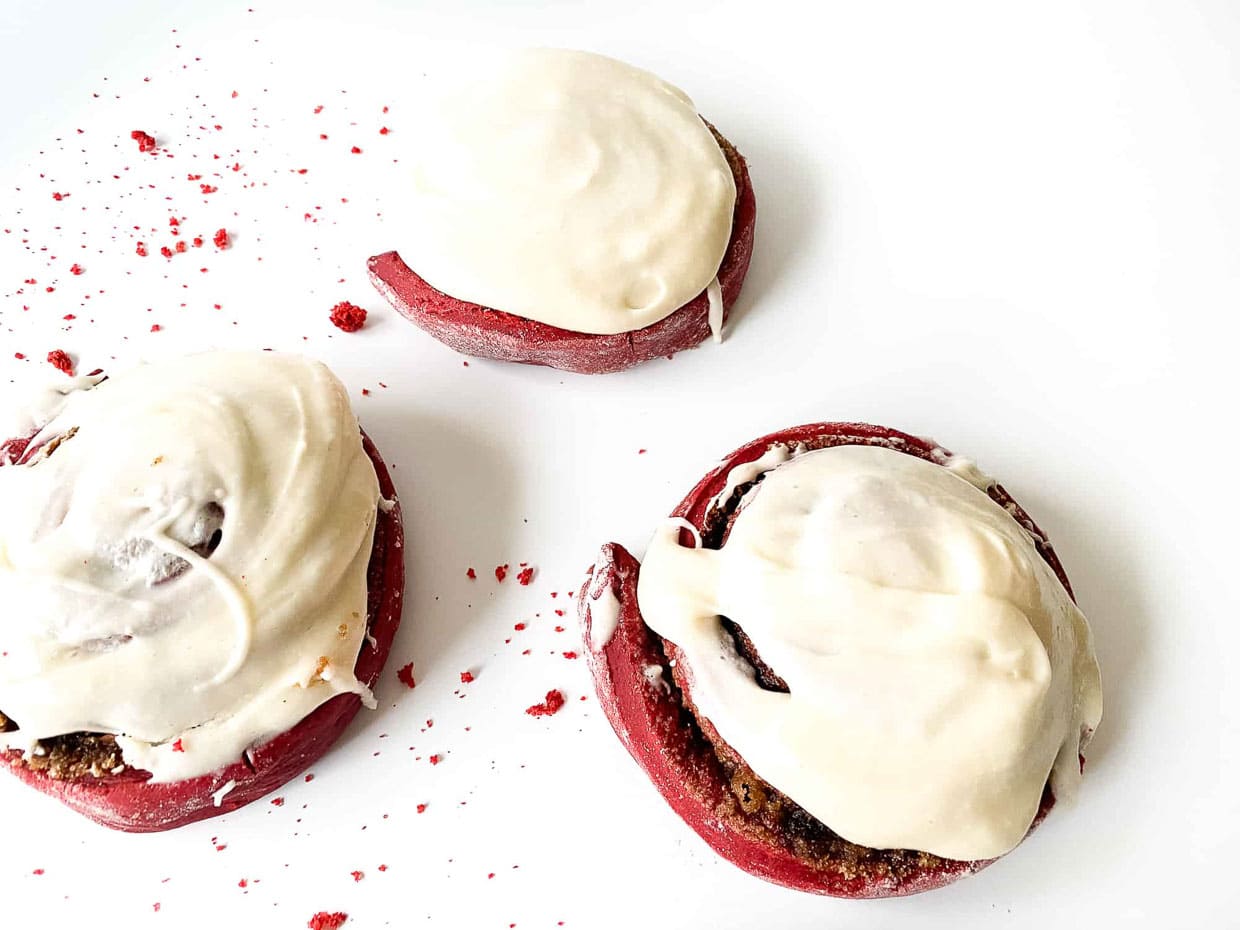 Red velvet cinnamon rolls top with smooth and creamy frosting.