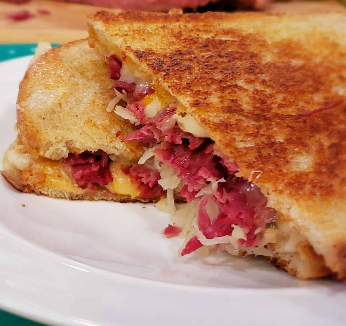 Grilled Reuben sandwich sliced diagonally showing corned beef and kraut.