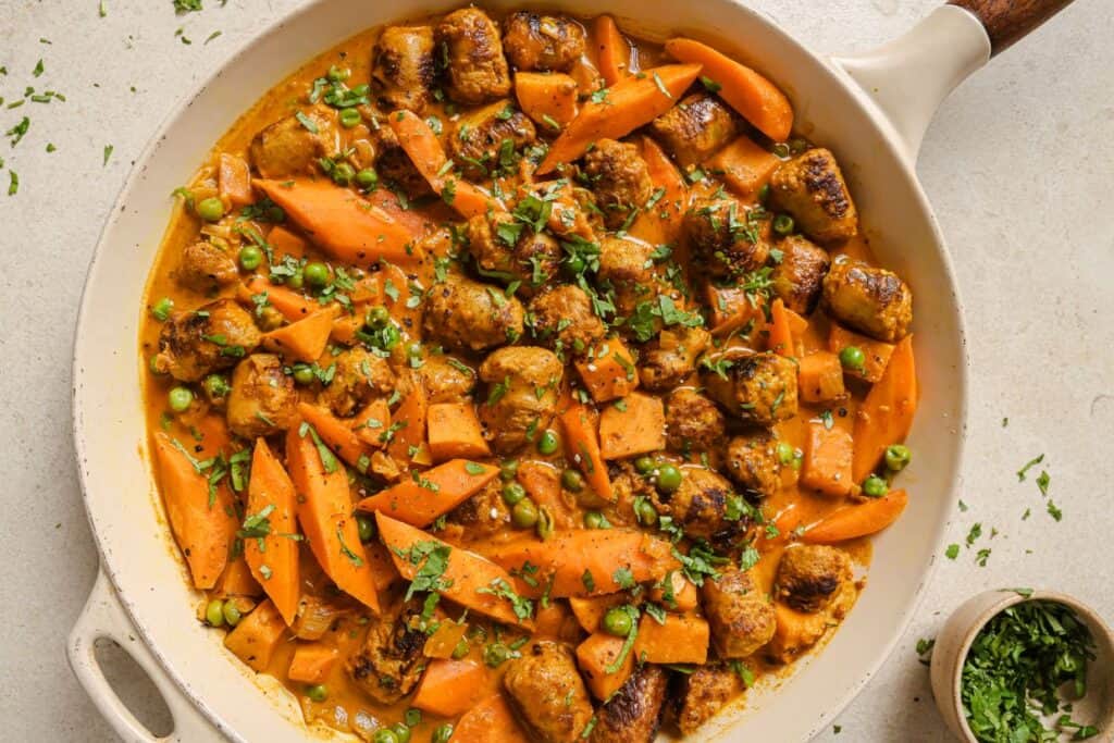 A skillet filled with carrots and sausages.