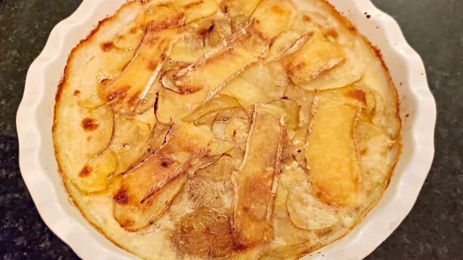 Image shows a closeup of a casserole of Smoked Brie Potato Gratin.