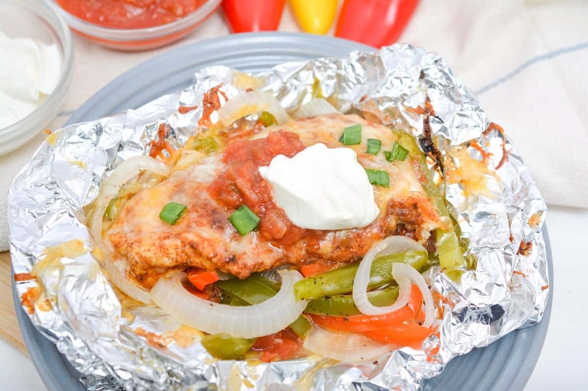 Chicken fajitas in foil with peppers, onions and sour cream.