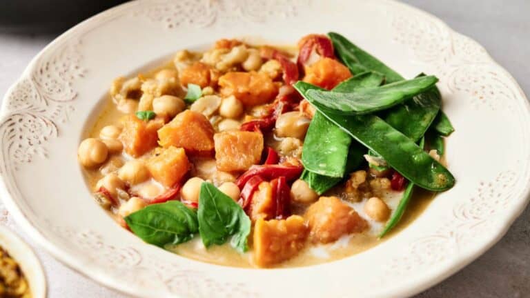 A bowl of sweet potato curry with peas and carrots.