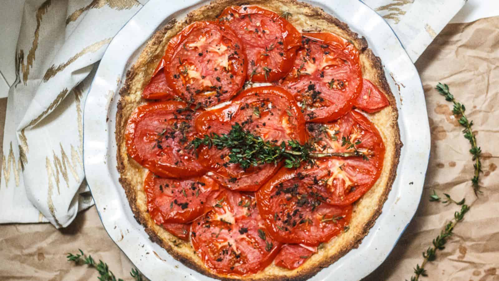 A pie with tomatoes and thyme on top.