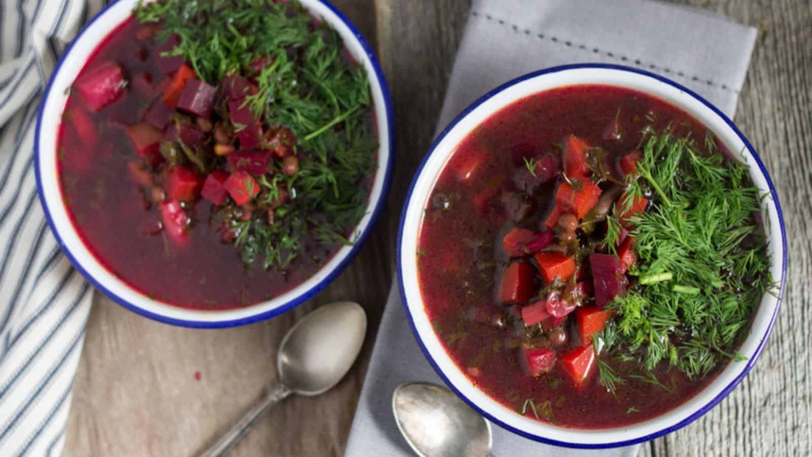 Two bowls of beet soup on a wooden table.