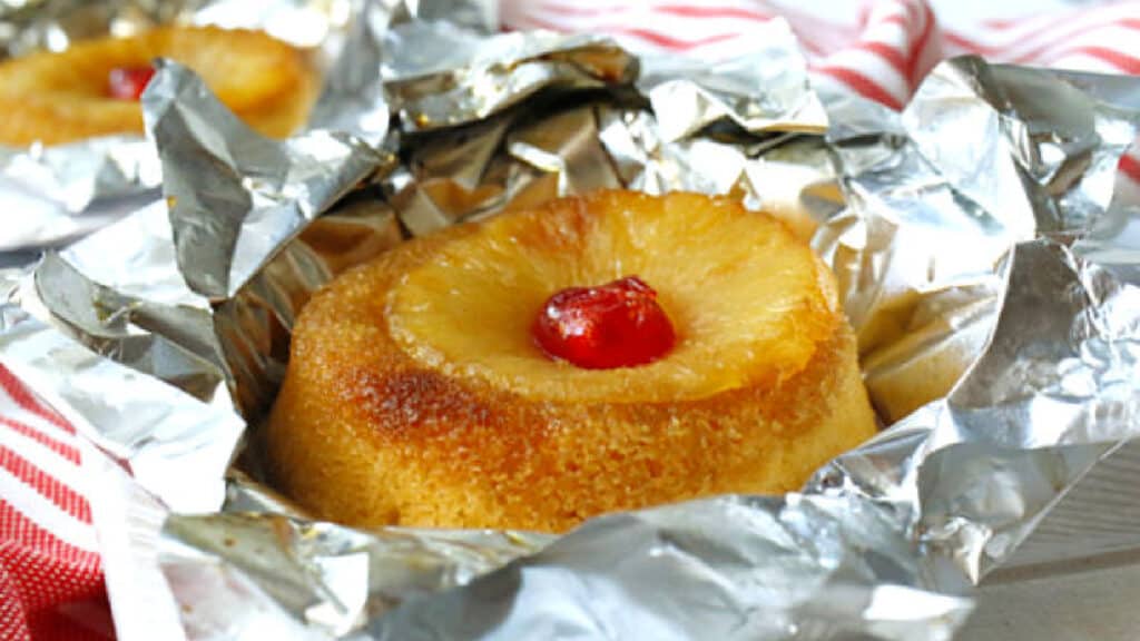 A pineapple upside down cake in foil with a cherry on top.