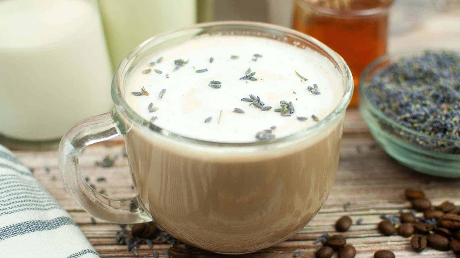 A latte with lavender and coffee beans on a wooden table.