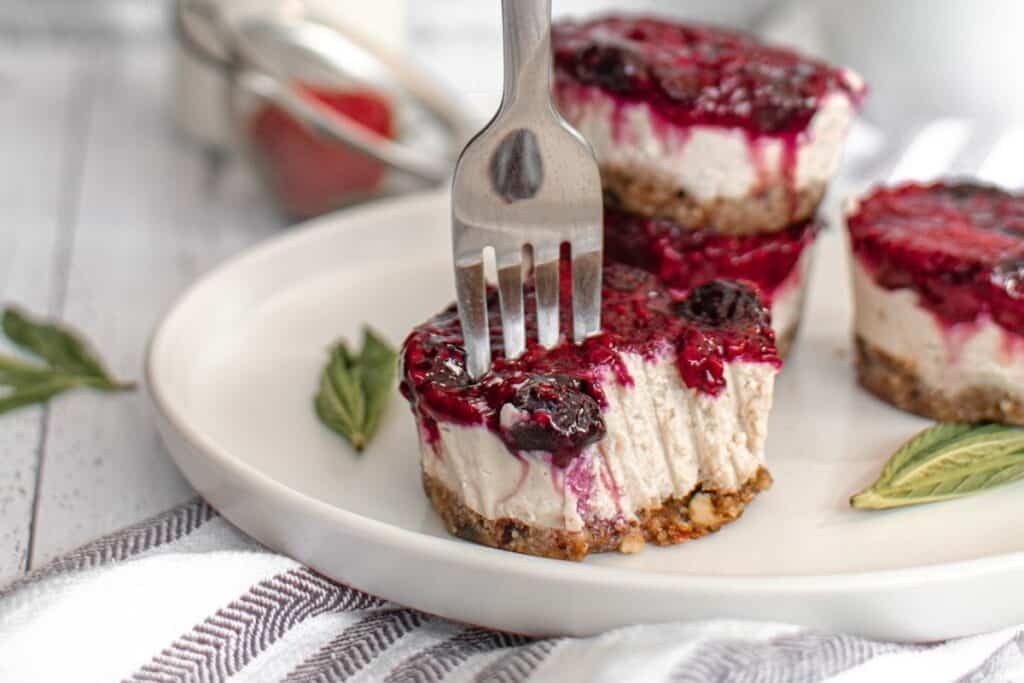Berry cheesecakes with a fork on a plate.