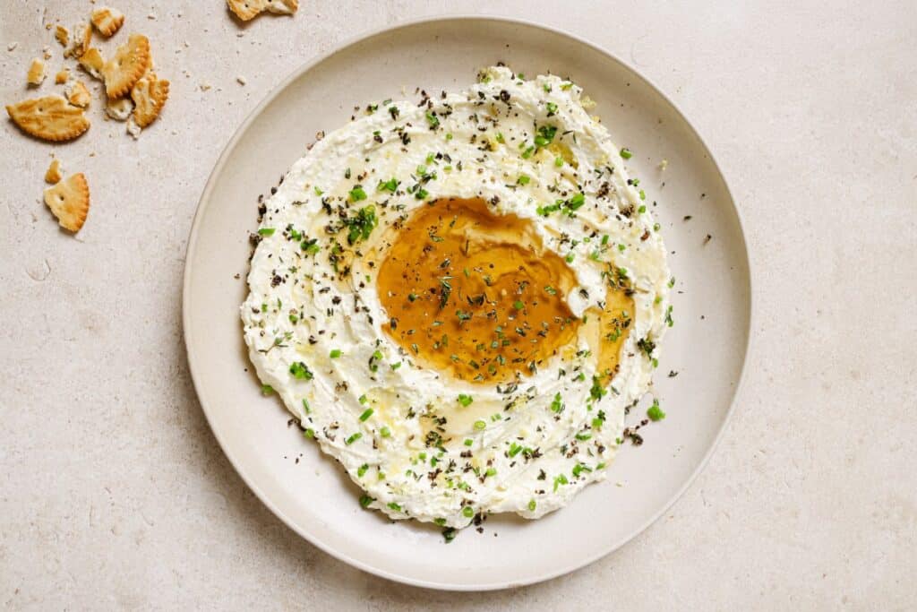 A plate of whipped feta with honey and crackers on it.
