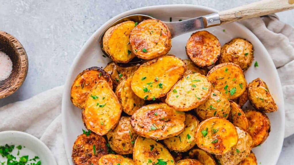 Roasted potatoes on a white plate with parsley.