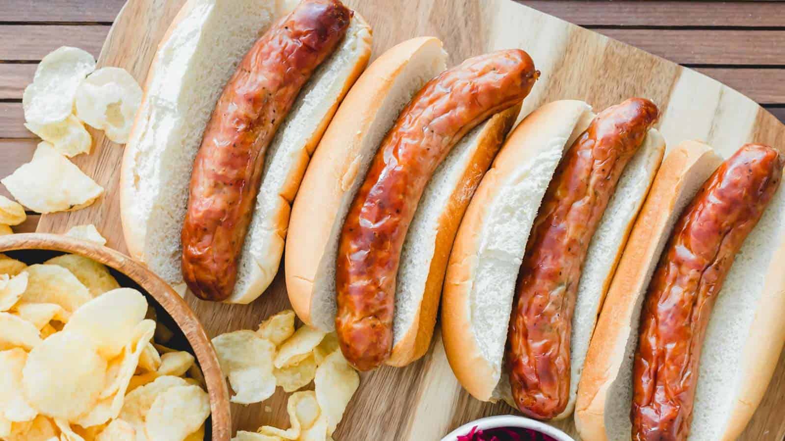 Air fryer brats on buns with potato chips on the side.