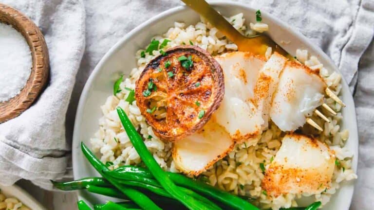 A white plate with cod and green beans on it.