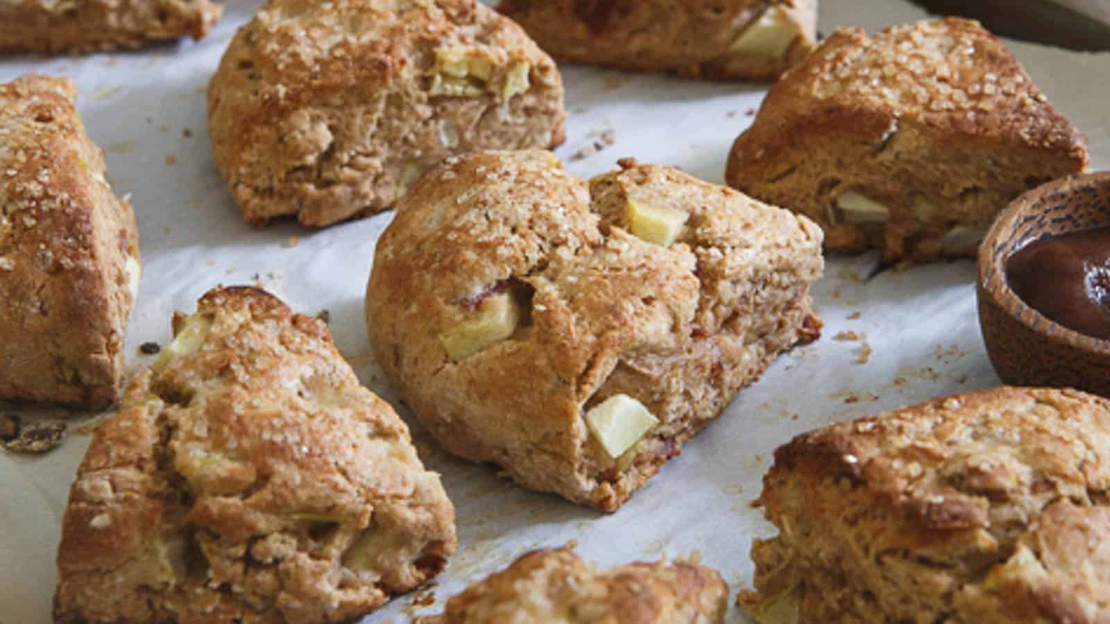 Apple bacon scones on parchment paper with apple butter in a bowl.