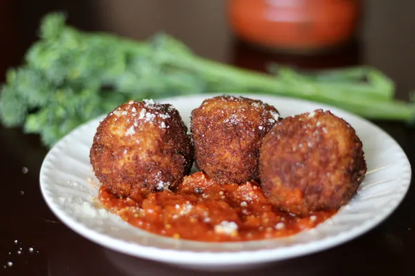 Three meatballs with sauce on a plate.