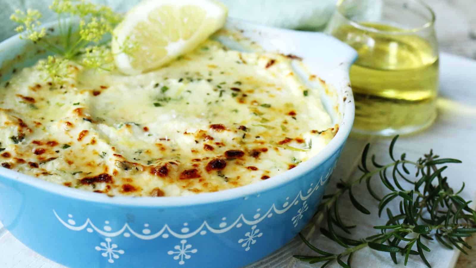 Baked ricotta cheese in a blue casserole dish with sliced bread.