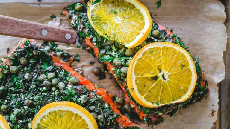 Salmon with orange slices on a baking sheet.